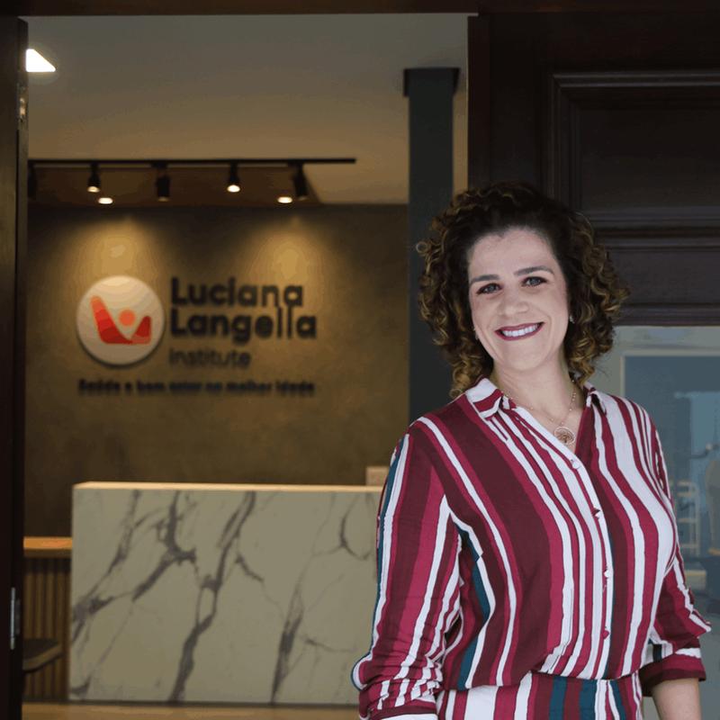 Luciana Langella na recepção da clínica, com o logo do instituto ao fundo
